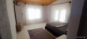 a bedroom with a bed and two large windows at Likya Vadi Evleri Nature and tranquility in Antalya