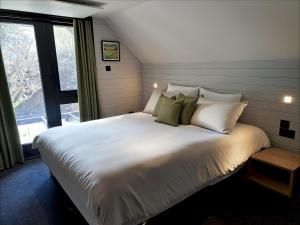a large white bed in a room with a window at Cardinham Lodge 3 bedroom - max 6 occ - VP4 in Looe