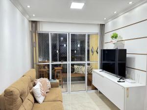 a living room with a couch and a flat screen tv at Apto completo com ar, piscina 2 quartos in Camaçari