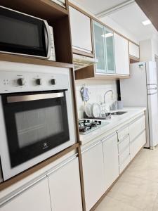 a kitchen with white cabinets and a microwave at Apto completo com ar, piscina 2 quartos in Camaçari