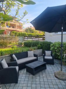 a patio with a couch and chairs and an umbrella at Apartment Lavanda in Pješčana Uvala