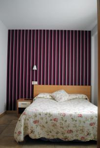 a bedroom with a bed and a red stripped wall at Hostal La Cortijana in Logroño