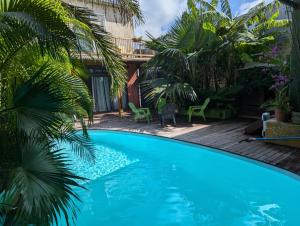 a swimming pool in a yard with palm trees at La Villa du Patio Parenthèse familiale Piscine 4 in Saint-Pierre