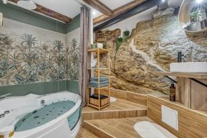 a bathroom with a tub and a rock wall at Secret room jacuzzi vieille ville Annecy in Annecy +16 photos