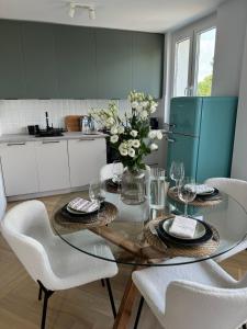 a kitchen with a glass table with chairs and a refrigerator at Studio 77 - nowoczesny apartament w Otwocku in Otwock