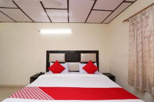 a bedroom with a large bed with red pillows at Hotel O Country Lodge in Dharamshala