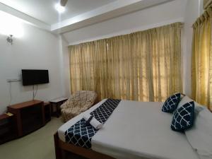 a bedroom with a bed and a chair and a television at Abids Inn Homestay in Bangalore