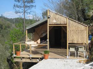 ein kleines Haus mit einer Hängematte und einer Veranda in der Unterkunft African Tent in Ponte da Barca