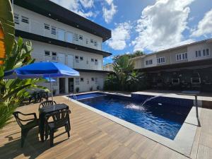 a patio with a pool and a table and an umbrella at Chalés do Bona Loft 18 in Ubatuba