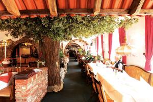 a row of tables in a restaurant with a tree at Hotel Restaurant Adria Kroatien in Bad Ems