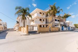 a white house with palm trees on the side of a street at B&B Gioiello del Mare in Torre Lapillo