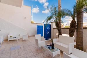 a patio with white chairs and palm trees at B&B Gioiello del Mare in Torre Lapillo +15 photos
