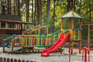 a playground with a slide in the sand at Domki Leśne Uroczysko in Ustka
