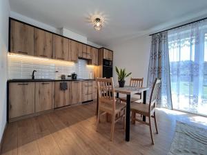 a kitchen with wooden cabinets and a table and chairs at Willa Górski Relaks in Sromowce Niżne