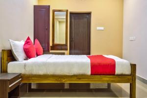 a bedroom with a bed with red and white pillows at Grand Ocean Inn in Puducherry