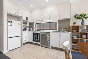 a kitchen with white appliances and a wooden table at KozyGuru | Austral | Charming 4Bedroom Family Home in Austral