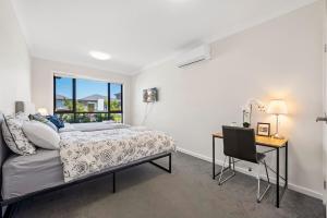 a bedroom with a bed and a desk and a window at KozyGuru | Austral | Charming 4Bedroom Family Home in Austral