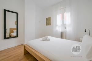- une chambre blanche avec un grand lit blanc et un miroir dans l'établissement Estilo con parking para 4, vive La Latina, à Madrid