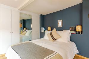 - une chambre avec des murs bleus et un lit avec des oreillers blancs dans l'établissement STRAS'LOFT - Hypercentre - Haut de Gamme - Cathédrale - Confort - Calme, à Strasbourg