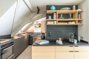 une cuisine avec un comptoir noir et des armoires en bois dans l'établissement STRAS'LOFT - Hypercentre - Haut de Gamme - Cathédrale - Confort - Calme, à Strasbourg