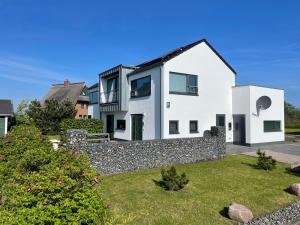 een wit huis met een stenen muur bij Ferienwohnung Wasser mit Sauna Kamin Meerblick und Dachterrasse nahe Ostsee auf Rügen in Dranske