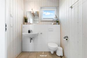 a white bathroom with a toilet and a sink at Ferienhaus Strandläufer Olpenitz in Olpenitz +28 photos