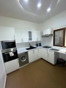 a kitchen with white cabinets and a sink and a refrigerator at Magnifique Appartement in Dakar