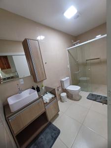 a bathroom with a sink and a toilet and a shower at Apartamento Família Termas in Gravatal