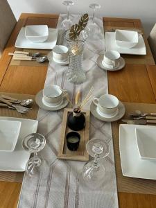 - une table avec des assiettes blanches et des verres à vin dans l'établissement Cosy 3-Bed Retreat - Garden Parking & Bbq, à Birmingham