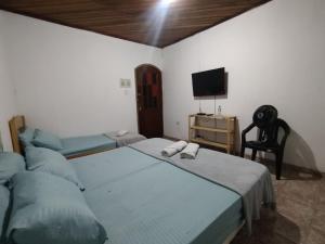 a bedroom with two beds and a tv and a chair at Haja Luz Casa Pousada no Centro de Itaquaquecetuba in Itaquaquecetuba