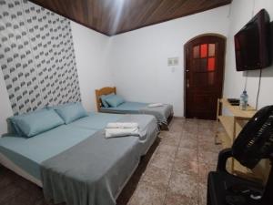 two beds in a room with a tv and a tv at Haja Luz Casa Pousada no Centro de Itaquaquecetuba in Itaquaquecetuba