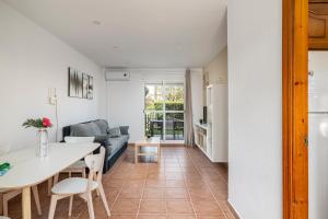 eine Küche und ein Wohnzimmer mit einem Tisch und einer Couch in der Unterkunft Jardín del Golf apartamento con jardín privado in Chiclana de la Frontera