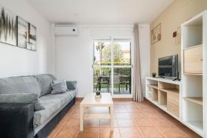 ein Wohnzimmer mit Sofa und Tisch in der Unterkunft Jardín del Golf apartamento con jardín privado in Chiclana de la Frontera