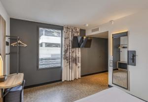 a room with a bed and a table and a window at B&B HOTEL Bordeaux Bassins à flot in Bordeaux
