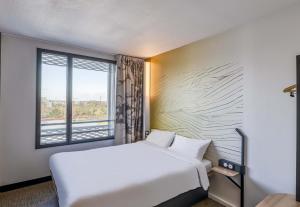 a hotel room with a bed and a window at B&B HOTEL Bordeaux Bassins à flot in Bordeaux