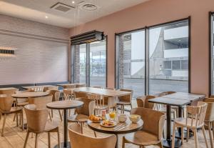 a restaurant with tables and chairs and windows at B&B HOTEL Bordeaux Bassins à flot in Bordeaux