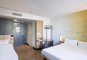 a hotel room with two beds and a desk at B&B HOTEL Bordeaux Bassins à flot in Bordeaux