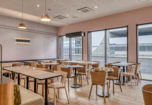 a restaurant with tables and chairs and windows at B&B HOTEL Bordeaux Bassins à flot in Bordeaux
