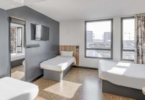 a room with two beds and a tub and a sink at B&B HOTEL Bordeaux Bassins à flot in Bordeaux