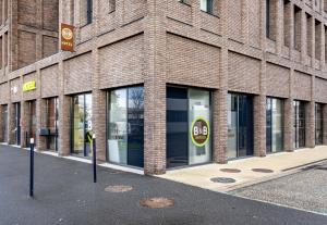 a facade of a brick building with glass windows at B&B HOTEL Bordeaux Bassins à flot in Bordeaux