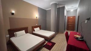 a small room with two beds and a chair at Lush Garden Hostel in Arusha