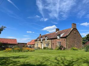 Dale View Cottages and Rooms - Whitby في Stainsacre: منزل من الطوب القديم مع ساحة خضراء