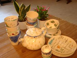 a table topped with cups and saucers and potted plants at Chicchi Di Melograno in Modica