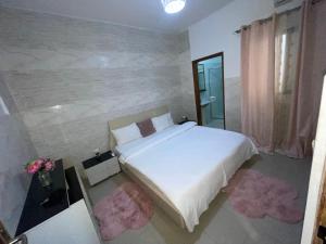 a bedroom with a white bed and a stone wall at Paradis Appartement in Ngor