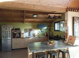 una cucina con soffitti in legno e una grande isola con sgabelli da bar di Maison familiale Saint Leu a Saint-Leu Altre 4 foto