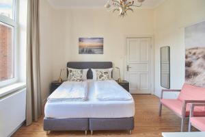 Un dormitorio con una cama y una silla rosa. en Villa Dünenblick Doppelzimmer Bernstein, en Timmendorfer Strand 10 fotos más