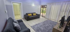 een woonkamer met een bank en een televisie bij Meerensee Cottage in Richards Bay