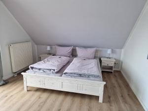 ein weißes Schlafzimmer mit 2 Betten und 2 Nachttischen in der Unterkunft Ferienwohnung An der Karlskuppe in Eisenach