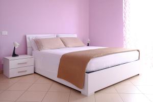 a bedroom with a white bed and a white night stand at Andrea's House in Locri