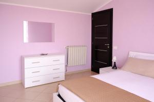 a bedroom with a white bed and a black door at Andrea's House in Locri